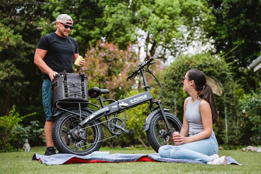 A couple enjoys a picnic in the park with an electric bike on a sunny day.